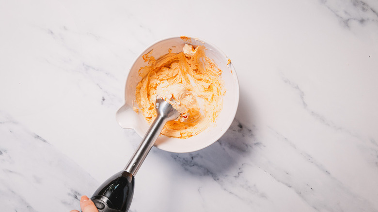 Cream cheese topping in bowl with immersion blender