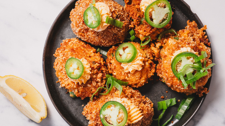 Overhead view of crab cake jalapeño popper bites on a black plate