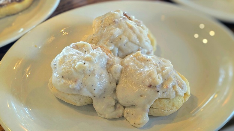 Three biscuits with white sausage gravy on a white oval plate