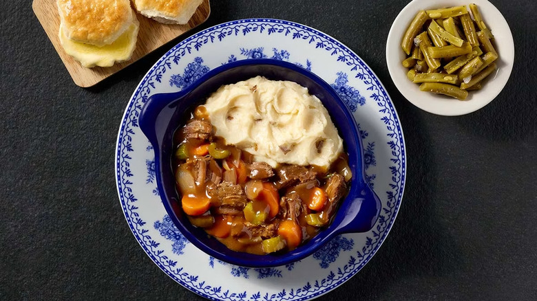 Cracker Barrel's beef pot roast alongside mashed potatoes, served with a side of green beans and biscuits