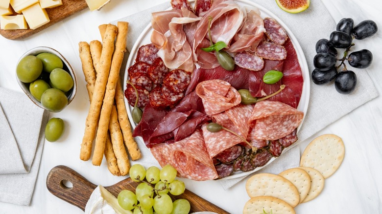 Charcuterie board with crackers and bread sticks
