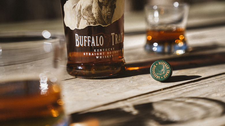 Bottle of Buffalo Trace on a table beside a bottle cap