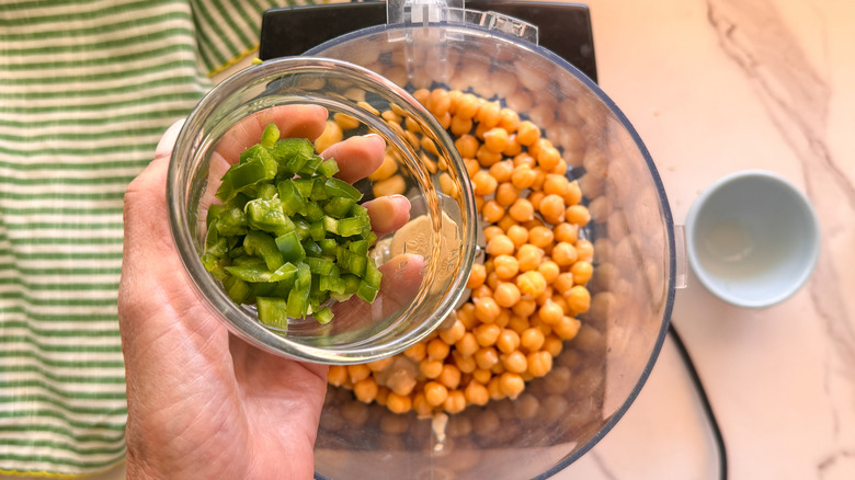 hand adding jalapeno to processor
