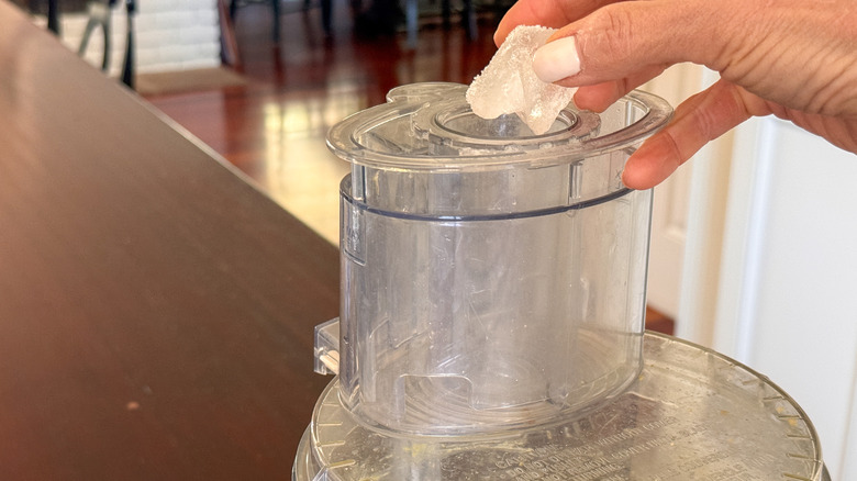 hand adding ice cubes to processor
