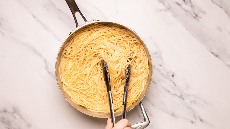 Adding pasta to creamy sauce.