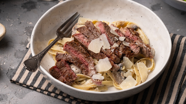 fettuccine pasta with steak in bowl