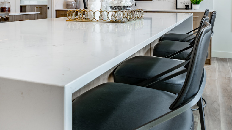 Black chairs lined up a white kitchen island
