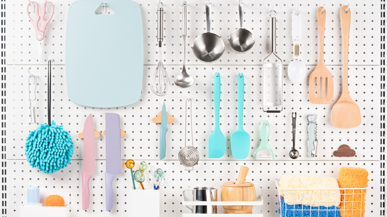 Front view of neatly organized kitchen utensils hanging on a white pegboard