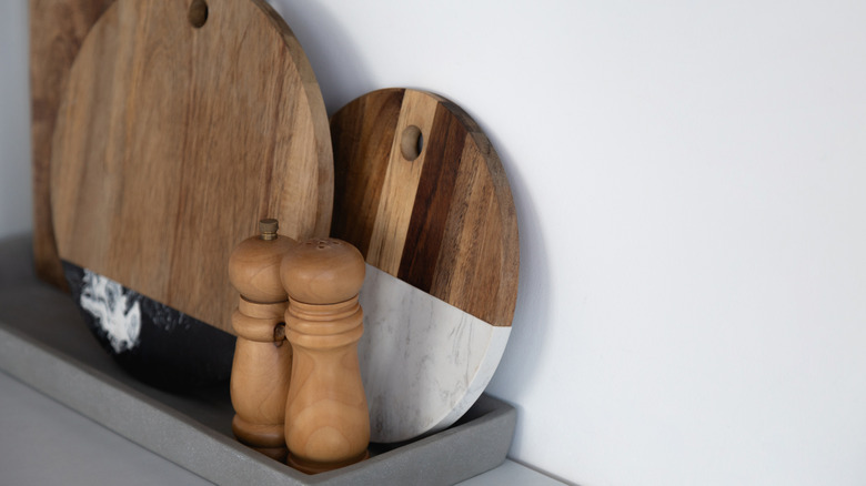 Three cutting boards placed near salt and pepper shakers against a white wall