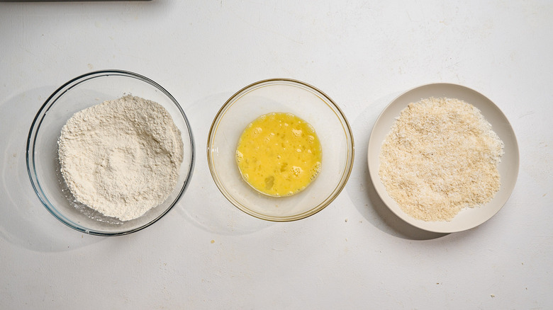flour, eggs, and breadcrumbs arranged in bowls on a table