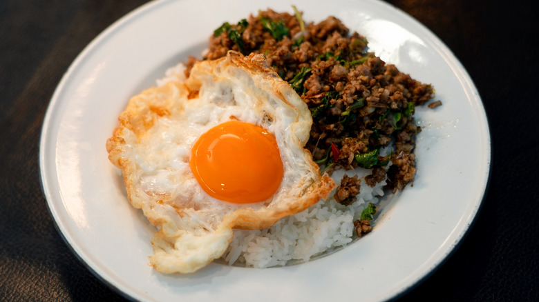 A plate of Thai food with a crispy fried egg.