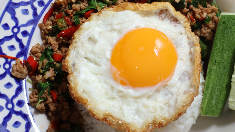 Close up of Thai fried egg over a Thai dish.