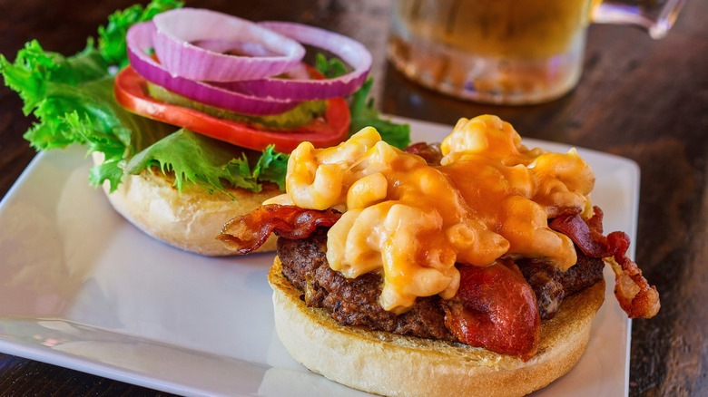 mac and cheese on buurger with bacon lettuce tomato and onion.
