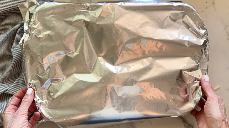 hands holding covered dish