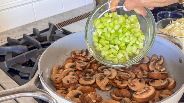 hand adding celery to pan
