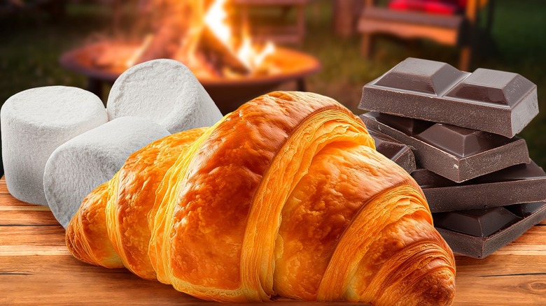 croissant and s'more ingredients in front of campfire