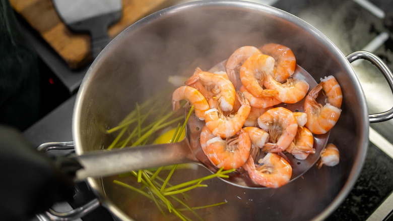 Poached shrimp being pulled from a pot of water