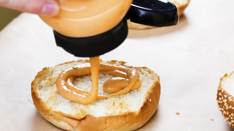 Burger sauce squeezing out onto a bun
