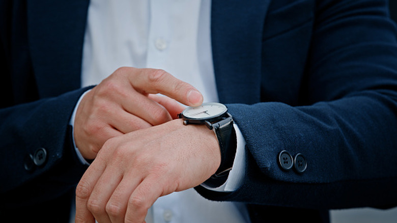 Close up of hand touching wristwatch