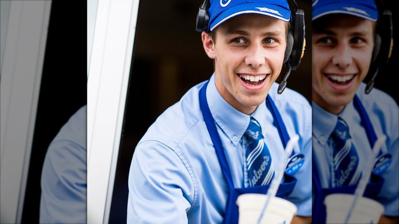 Mirrored image of smiling Culver's worker at drive-thru window