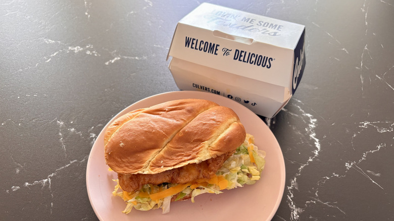 a Culver's fish sandwich on a plate with its cardboard carton placed behind it