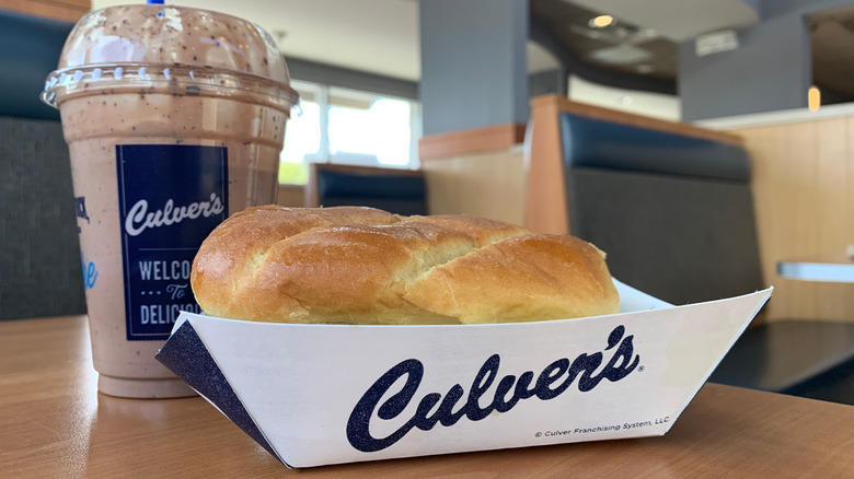 a Culver's sandwich in a cardboard tray and a plastic cup of milkshake on a table in one of the chain's restaurants