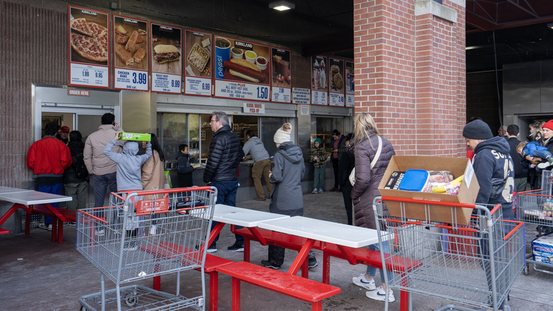 People waiting around with carts at a Costco food court