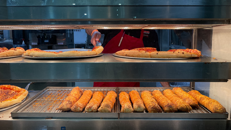Close up of costco food court counter with employee taking pizza from tray