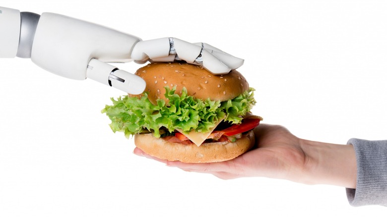 A robotic arm handing a burger to a human arm