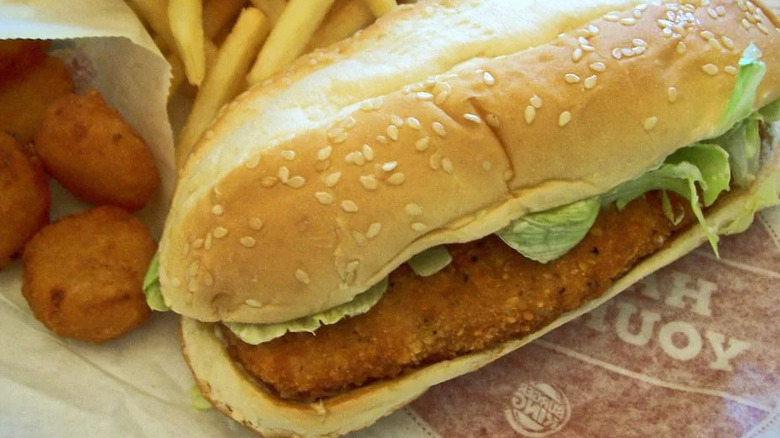 a Burger King Original Chicken Sandwich on its wrapper alongside french fries and another fried side