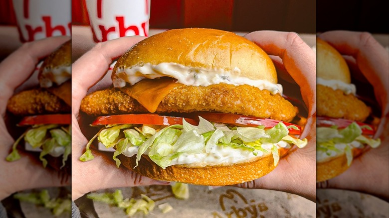 Hands holding Arby's Hawaiian Fish Deluxe Sandwich