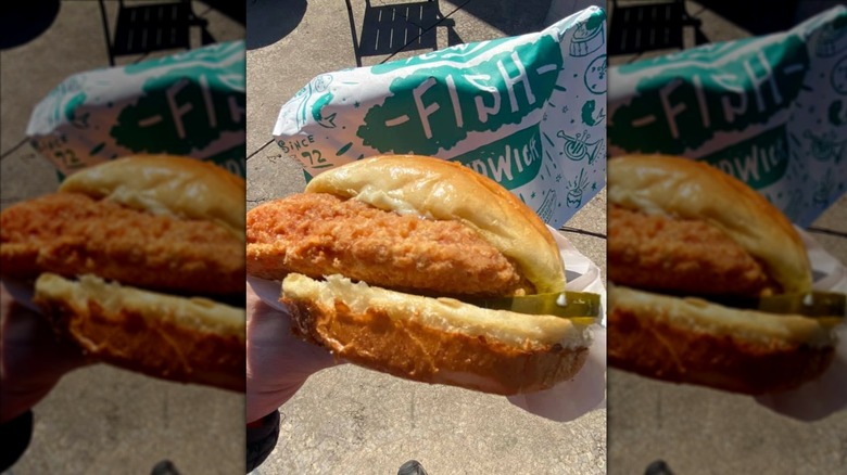 Hand holding Popeyes' Flounder Fish Sandwich outside