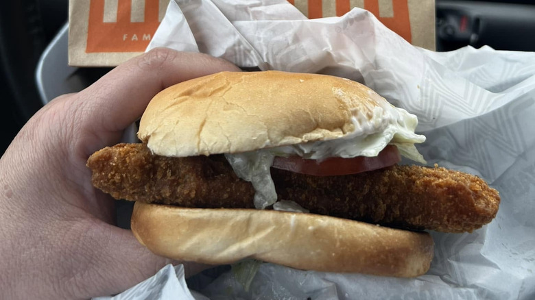 Hand holding Whataburger Whatacatch Sandwich in car