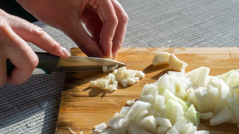 person cutting onion on chopping board