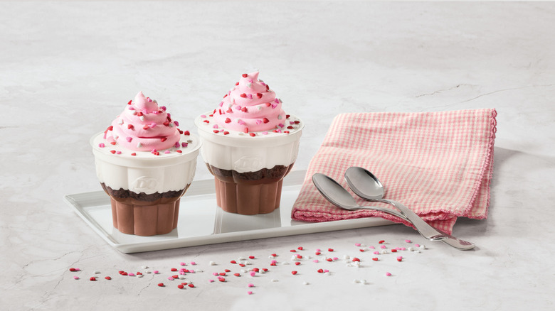 Two Dairy Queen Valentine's Cupcakes on a plate with a napkin and two spoons.