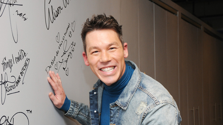 David Bromstad smiles next to an autographed wall