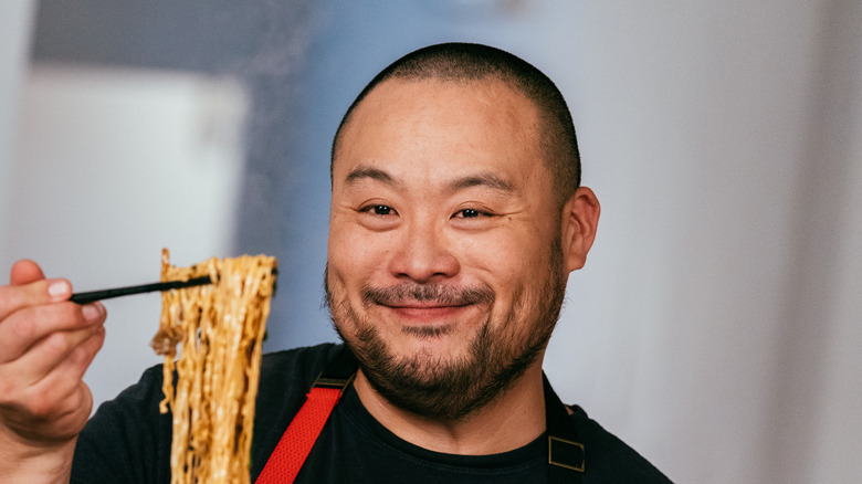 David Chang holding up noodles