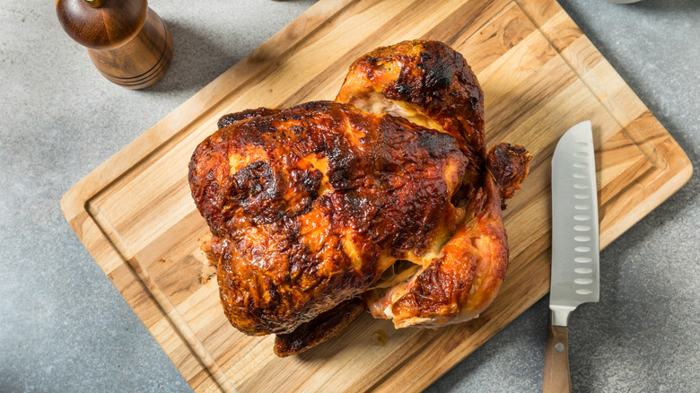 rotisserie chicken on wood board with knife