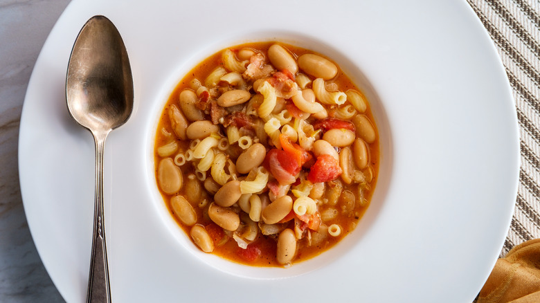 pasta fagioli in a white bowl with silver spoon
