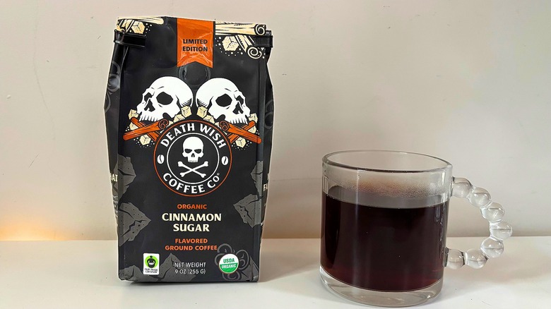 Bag of Death Wish Cinnamon Sugar coffee next to a clear mug of black coffee on a white table