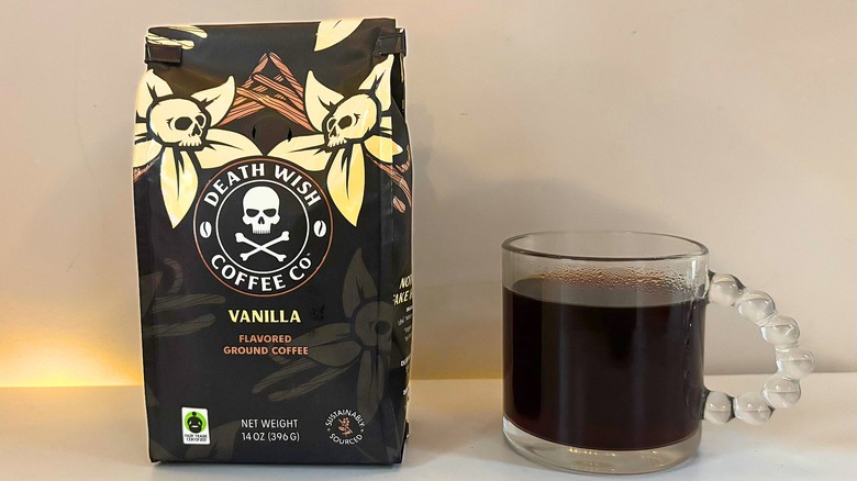 Bag of Death Wish Vanilla coffee next to a clear mug of black coffee on a white table
