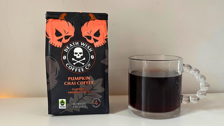 Bag of Death Wish Pumpkin Chai Coffee next to a clear mug of black coffee on a white table