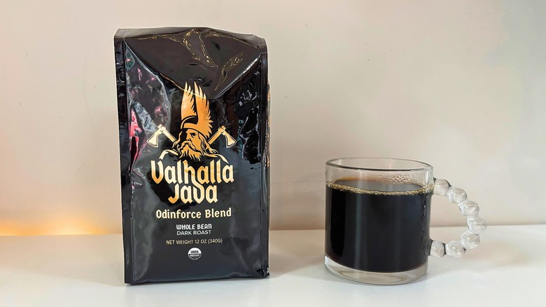 Bag of Death Wish Valhalla Java Odinforce Blend coffee next to a clear mug of black coffee on a white table