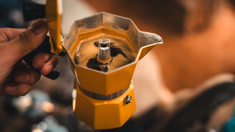 Decaf coffee brewing in a yellow moka pot