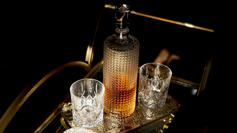 whiskey in decanter with two glasses on bar cart