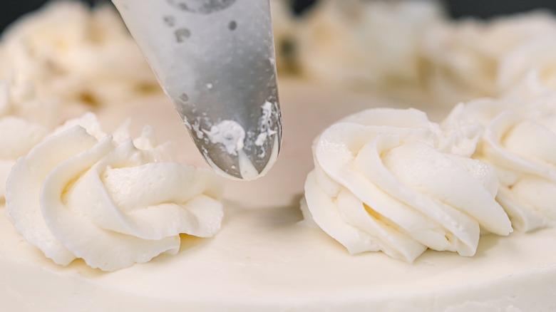 The aluminum chip of a Piping Bag piping white frosting onto a cake