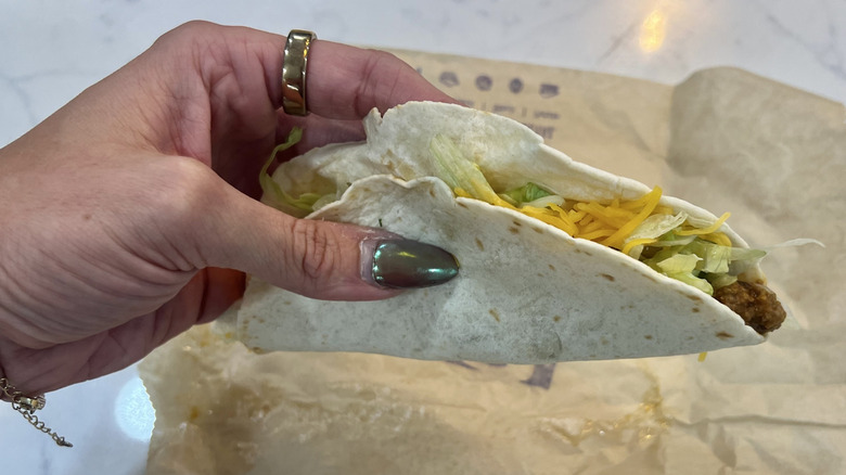 Hand holding Taco Bell Soft Taco over wrapper.