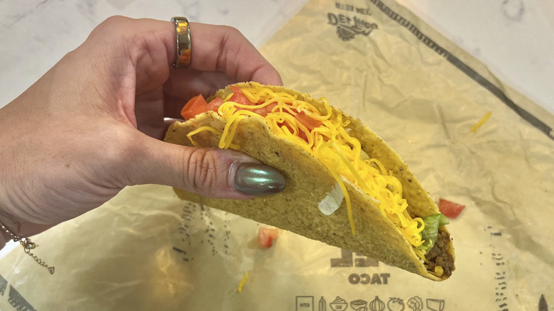 Hand holding The Del Taco over wrapper.