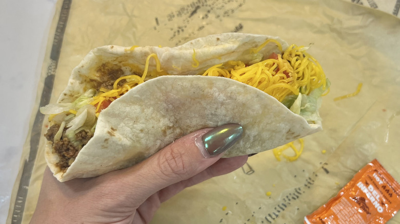Hand holding The Del Taco Soft over wrapper.