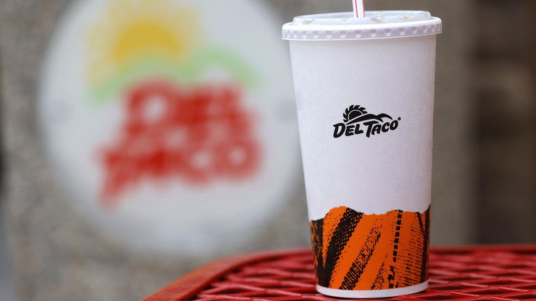 Del Taco cup in front of the sign
